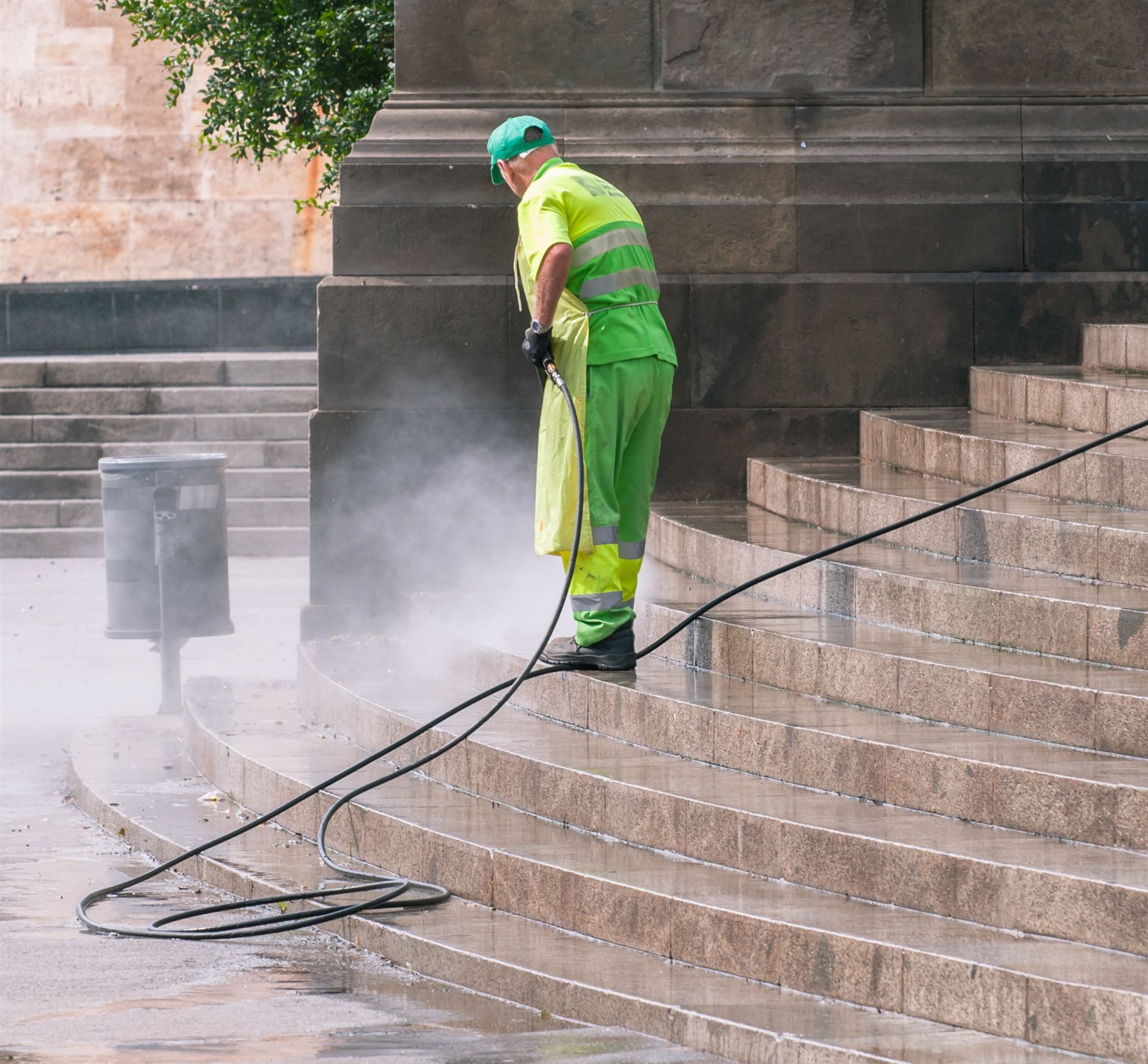 Arbeiter reinigt Steinstufen und Außenpflaster mit dem Hochdruckreiniger