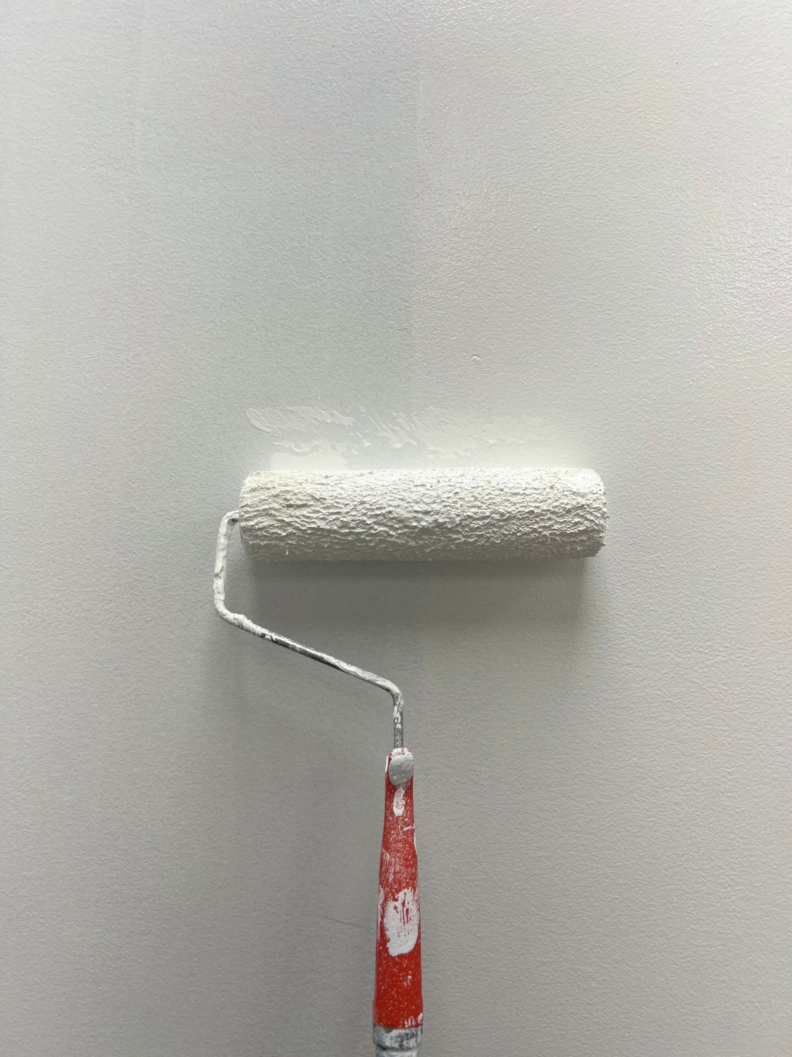 Farbrolle trägt einen frischen Anstrich auf eine Innenwand auf